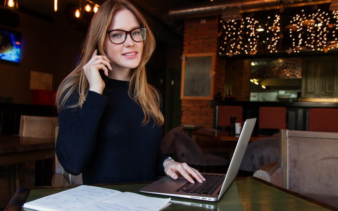 woman working on laptop and talking on phone about how to delegate tasks effectively